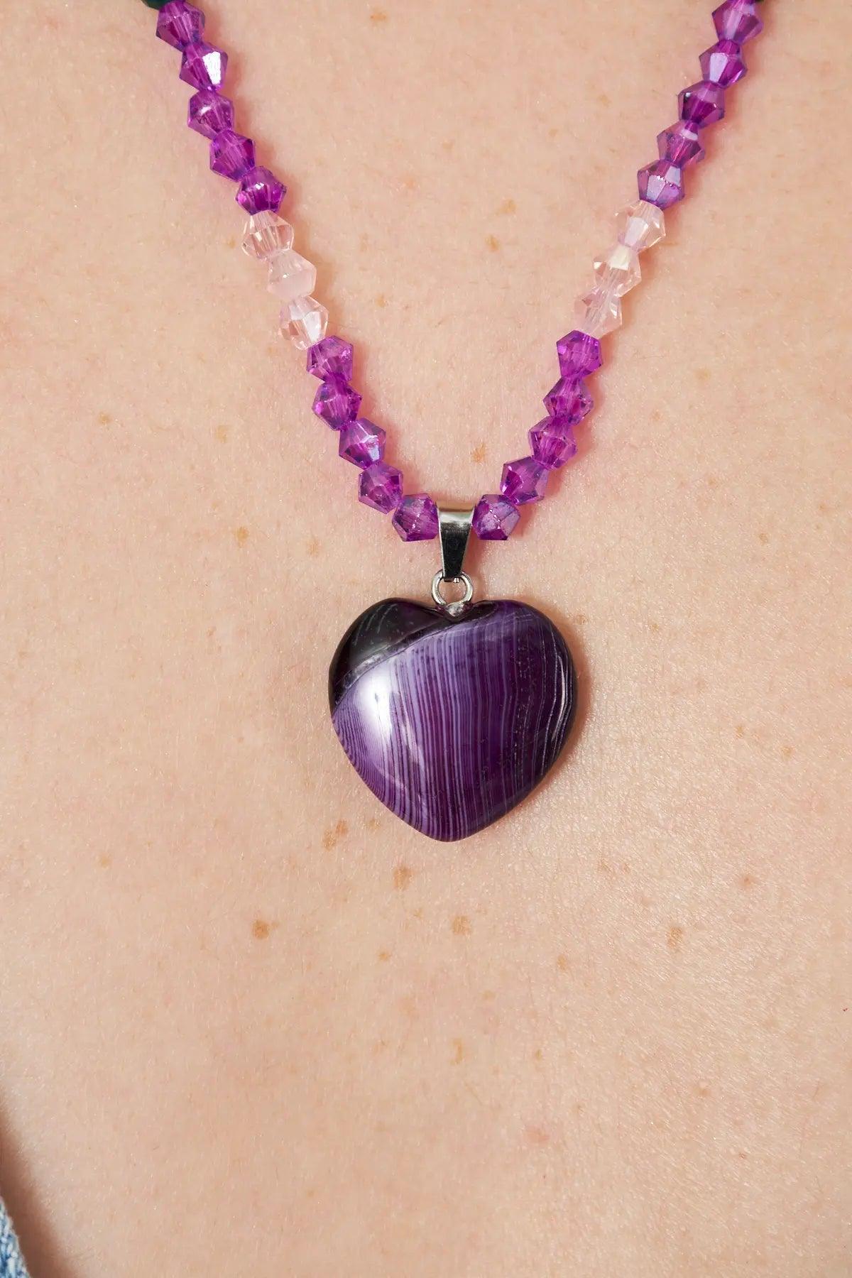 A stunning necklace featuring an amethyst heart-shaped pendant with faceted crystal beads in purple and pink tones, perfect for adding elegance to any outfit.